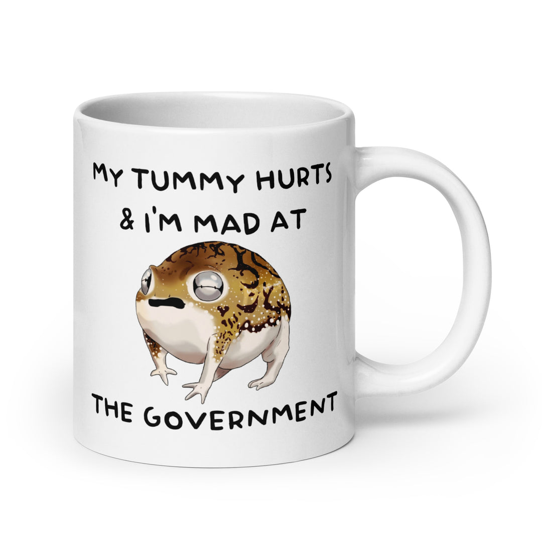 Funny Satire Coffee Mug featuring a frog with text about tummy aches and government frustration